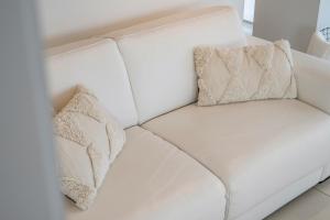 um sofá branco com duas almofadas em Gelijkvloers zeedijk appartement - lichtrijk en modern em Blankenberge