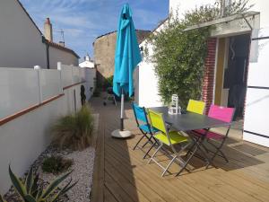 een patio met een tafel en stoelen en een parasol bij Des vacances à 4 à Talmont St Hilaire in Talmont