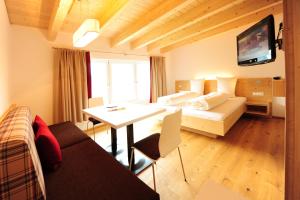 a room with a bed and a table and a television at AlpeLux Appartement an der Skipiste in Jerzens