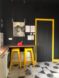 a laundry room with two yellow stools and a table at Suffolk pink house, Newmarket town centre in Newmarket
