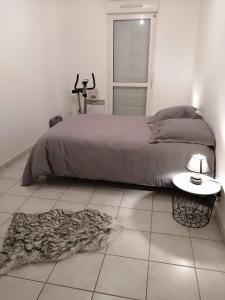 - une chambre avec un lit et un tapis sur un sol carrelé dans l'établissement appartement meublés, à Coutances