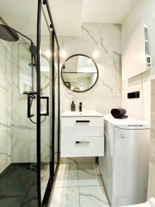 uma casa de banho com um chuveiro, um lavatório e um espelho. em BP Apartment VI em Toruń
