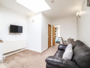 a living room with a leather couch and a flat screen tv at 493 Little Wakering Road in Southend-on-Sea