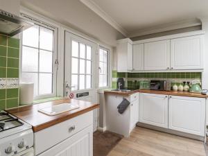 a kitchen with white cabinets and green tiles at 493 Little Wakering Road in Southend-on-Sea