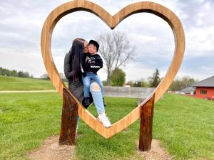 a woman and a boy sitting inside of a wooden heart at Na Golfu in Kestřany