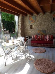 a patio with a table and chairs and a couch at Un jardin sur la colline in Claveyson