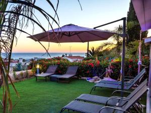 a patio with chairs and an umbrella and the ocean at Luxury Marissa Villa in Chlorakas