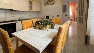 uma cozinha com uma mesa com cadeiras e uma tigela de flores em Welcomely - Casa del Minatore 2 em Gonnesa