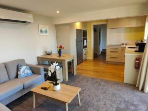 a living room with a couch and a table and a kitchen at Fully Renovated Hillside Apartment Close To City in Christchurch