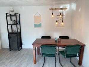 ein Esszimmer mit einem Holztisch und grünen Stühlen in der Unterkunft Sand & Soul in Scharbeutz