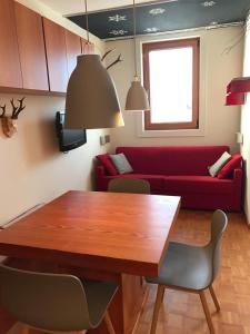 - un salon avec une table en bois et un canapé rouge dans l'établissement Appartamento con vista sull'Alpe di Siusi, à Bulla