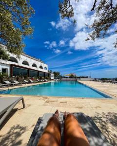 a person laying on a bench next to a swimming pool at Carpe Diem Cadaqués in Cadaqués