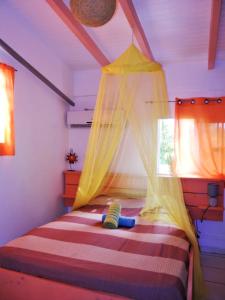 1 dormitorio con 1 cama con dosel y 2 ventanas en Bungalow d'une chambre avec vue sur la mer jardin clos et wifi a Deshaies, en Deshaies