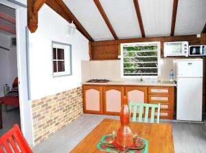 cocina con mesa de madera y nevera blanca en Bungalow d'une chambre avec vue sur la mer jardin clos et wifi a Deshaies, en Deshaies