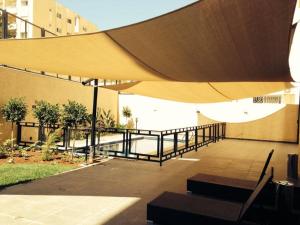 a patio with a large yellow umbrella and benches at Lijam Apartments in Amman