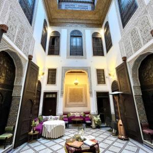 a room with a table and chairs in a building at Le Grand Alcazar - Riad in Fez