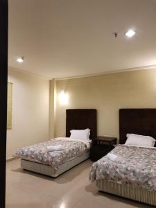 dos camas sentadas una al lado de la otra en una habitación en Spacious & Homey Apartment at Marina Island by JoMy Homestay en Lumut