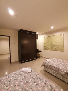 a bedroom with two beds and a large screen at Spacious & Homey Apartment at Marina Island by JoMy Homestay in Lumut