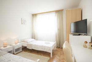 a white living room with a tv and a couch at Apartment Hanna in Split