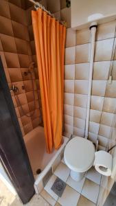 a bathroom with an orange shower curtain and a toilet at Perlica in Vodice