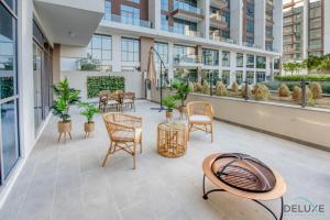 a patio with chairs and tables in a building at Serene 2BR at Acacia A Dubai Hills Estate By Deluxe Holiday Homes in Dubai