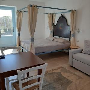 - une chambre avec un lit, une table et un canapé dans l'établissement Lispusada B&B, à Biancareddu