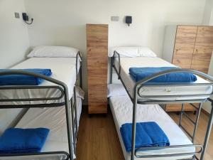 two bunk beds in a dorm room with blue pillows at Albergue La Huella in San Martín del Camino
