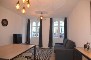 a living room with a couch and a table and two windows at Triplex 110 m2 centre historique avec jacuzzi DINAN in Dinan