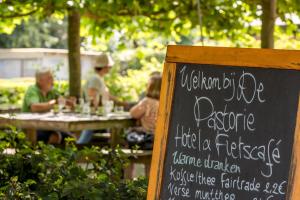 un grupo de personas sentadas en una mesa con una señal en De Pastorie, en Borgloon