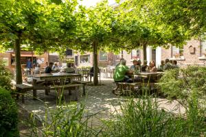 a group of people sitting at tables under trees at De Pastorie in Borgloon
