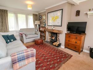 a living room with a couch and a television and a fireplace at 12 Kenmore Cottages in Oban