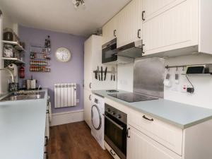 a kitchen with white cabinets and a sink at 12 Kenmore Cottages in Oban