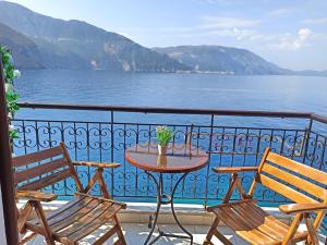 einen Tisch und Stühle auf einem Balkon mit Blick auf das Wasser in der Unterkunft Panorama Apartments in Asos