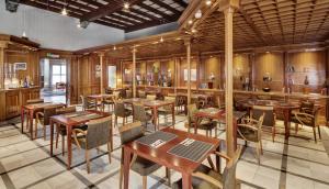 un restaurant avec des tables et des chaises en bois ainsi qu'un bar dans l'établissement Sercotel Toledo Renacimiento, à Tolède