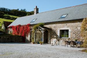 a stone building with tables and chairs in front of it at Higher Weddicott Barn in Newton Abbot