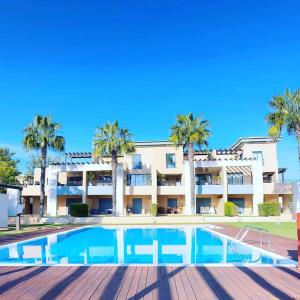 uma piscina em frente a um edifício com palmeiras em Janelas do Oceano - Casa de Ferias T3 Vilamoura em Vilamoura