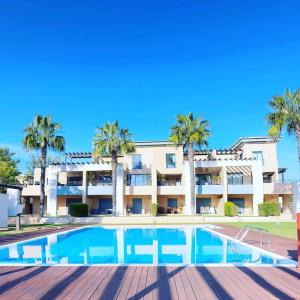 a swimming pool in front of a building with palm trees at Janelas do Oceano - Casa de Ferias T3 Vilamoura in Vilamoura