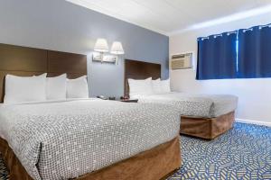 a hotel room with two beds and blue curtains at Econo Lodge in Hicksville