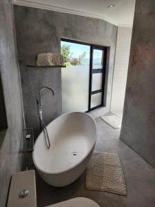 a large white tub in a bathroom with a window at Dinvorae in Southbroom
