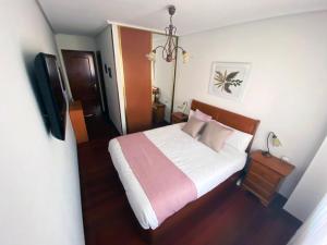 um quarto com uma cama com lençóis brancos e almofadas cor-de-rosa em Apt Las Olas Cotolino con parking a 2' de la playa em Castro-Urdiales