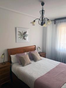 a bedroom with a bed and a chandelier at Apt Las Olas Cotolino con parking a 2' de la playa in Castro-Urdiales
