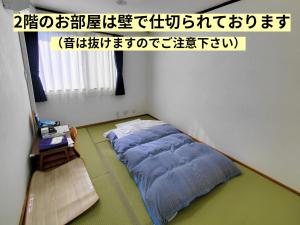 a room with a bed in the corner of a room at Tetsu no YA Guesthouse for Railfans in Fuefuki