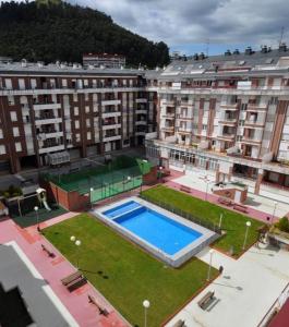 a large building with a swimming pool in the middle at Apt Las Olas Cotolino con parking a 2' de la playa in Castro-Urdiales