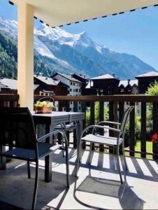 a balcony with a table and chairs and mountains at Mont Blanc 25, vue Mont blanc, balcon, parking in Chamonix-Mont-Blanc