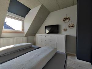 Schlafzimmer im Dachgeschoss mit 2 Betten und einem TV in der Unterkunft BooHouse in Zingst