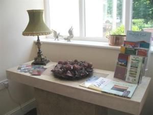 einen Tisch mit einer Lampe, Büchern und einem Fenster in der Unterkunft Hazelwood House in Bridgend
