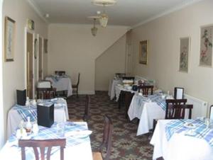una sala da pranzo con tavoli e sedie con tavoli bianchi di Hazelwood House a Bridgend