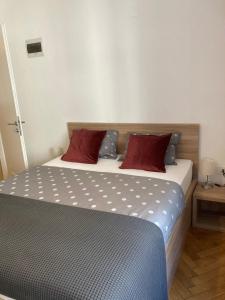 1 dormitorio con 1 cama con 2 almohadas rojas en Twix rooms, en Liubliana