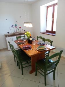 ein Esszimmer mit einem Holztisch und grünen Stühlen in der Unterkunft Casa Girasole in Buje