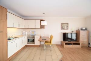 a kitchen with white cabinets and a table and a television at Haus Ankerplatz Apartment 2 2 in Büsum